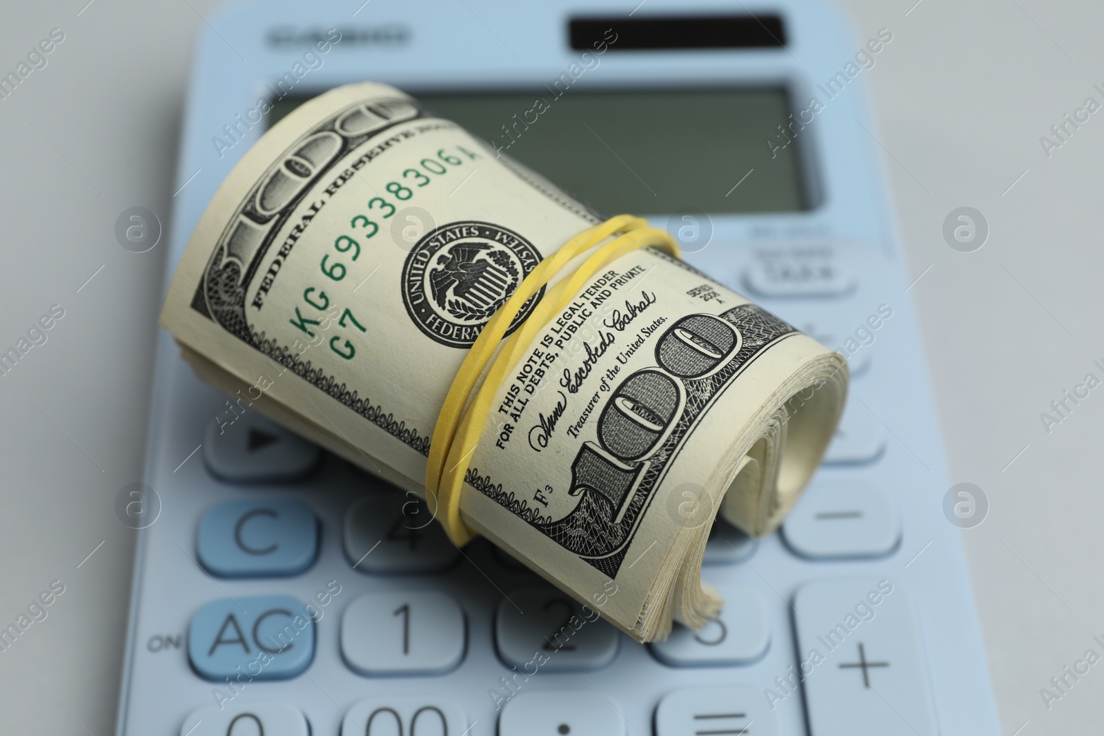 Photo of Money exchange. Dollar banknotes and calculator on gray background, closeup