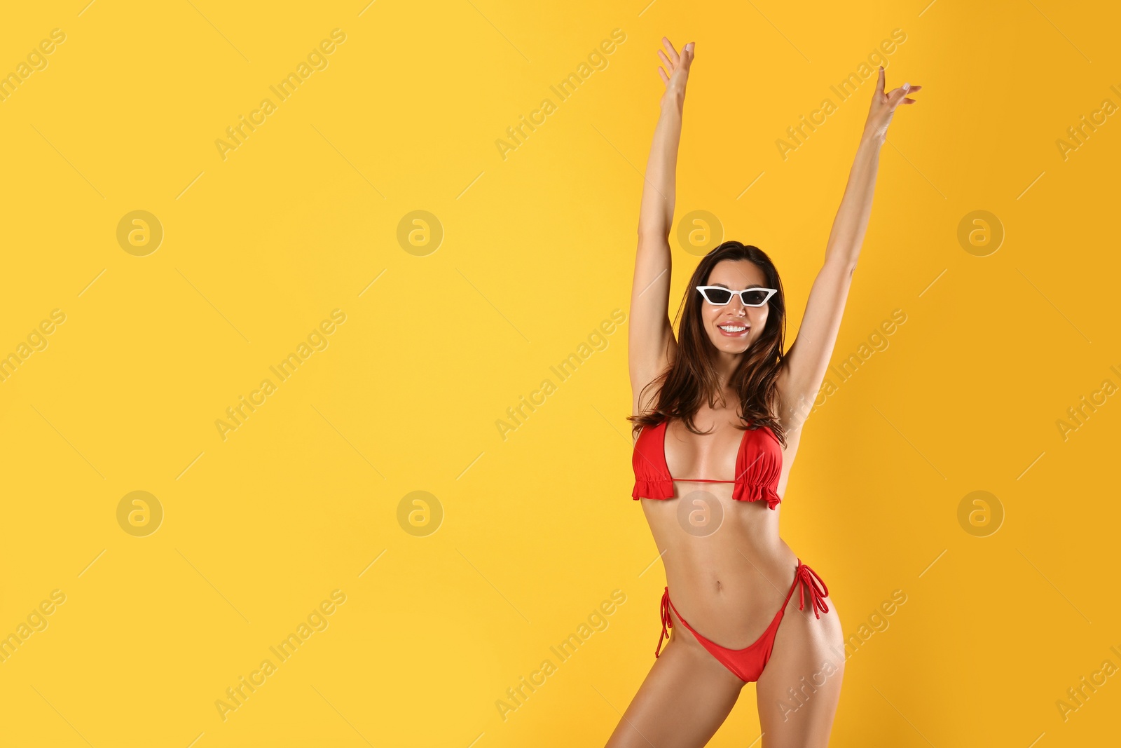 Photo of Beautiful woman in stylish bikini and sunglasses on yellow background. Space for text