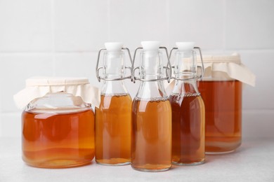 Photo of Tasty kombucha in glass jars and bottles on white table