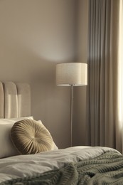 Photo of Stylish floor lamp near bed in room. Interior element