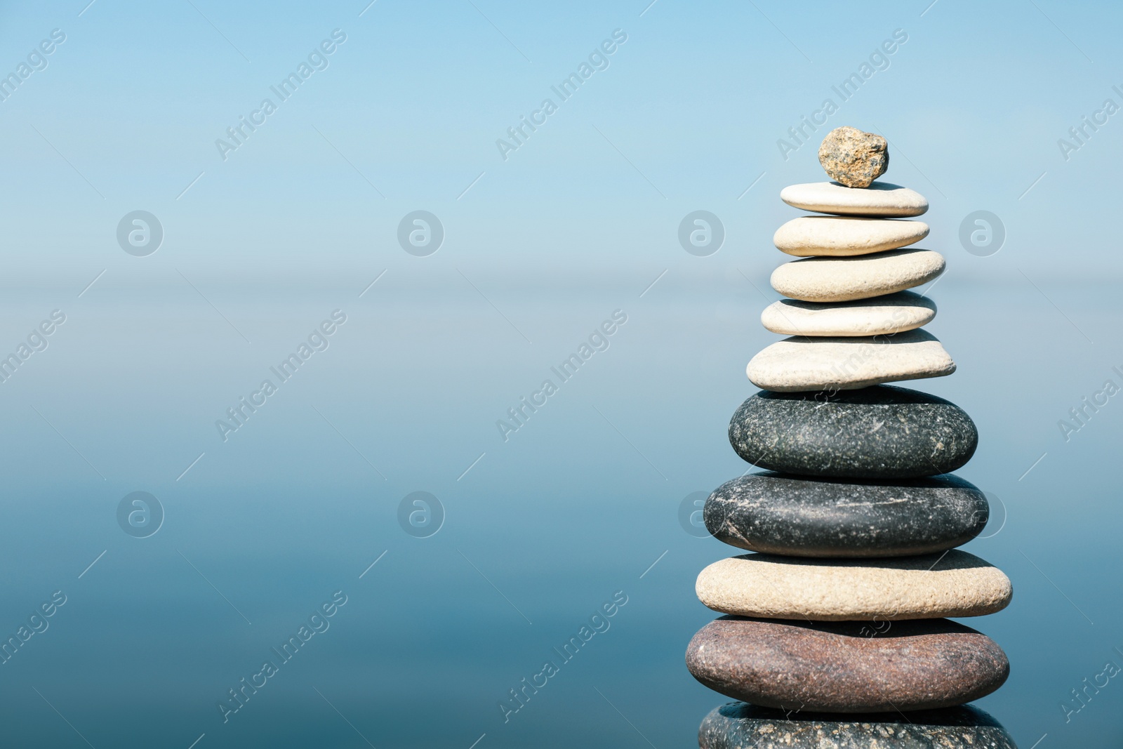 Photo of Stack of stones near sea, space for text. Harmony and balance concept