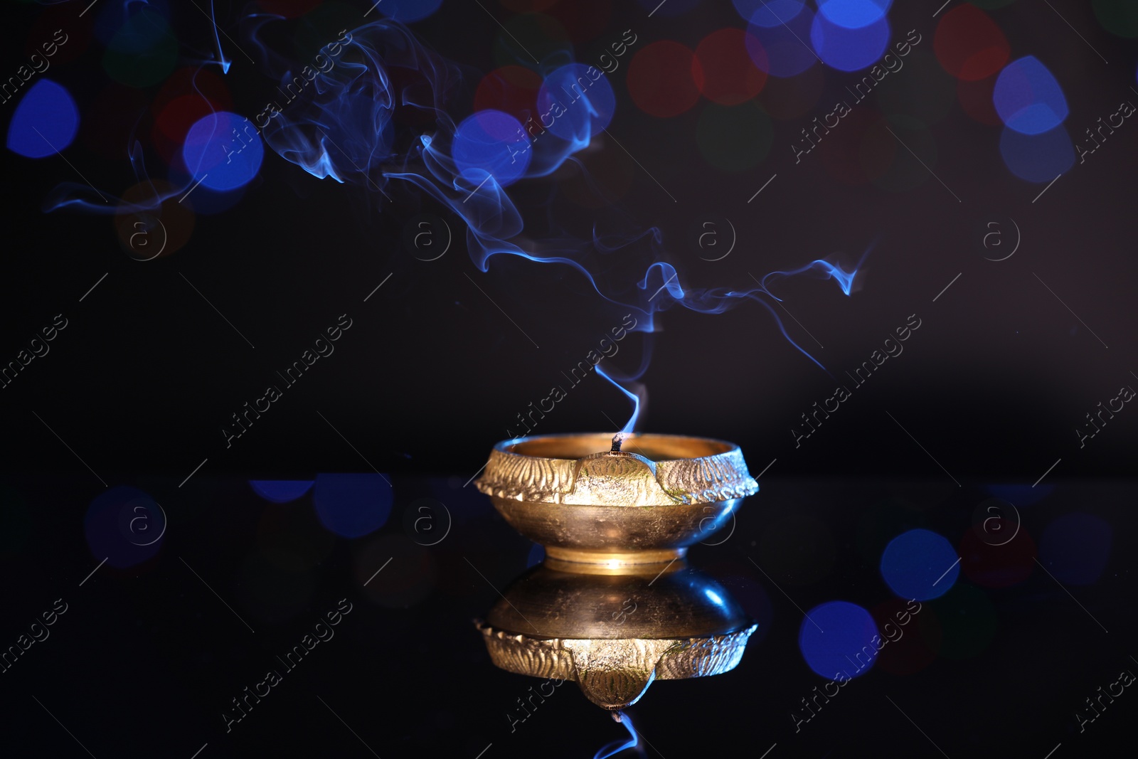 Photo of Blown out diya on dark background with blurred lights. Diwali lamp