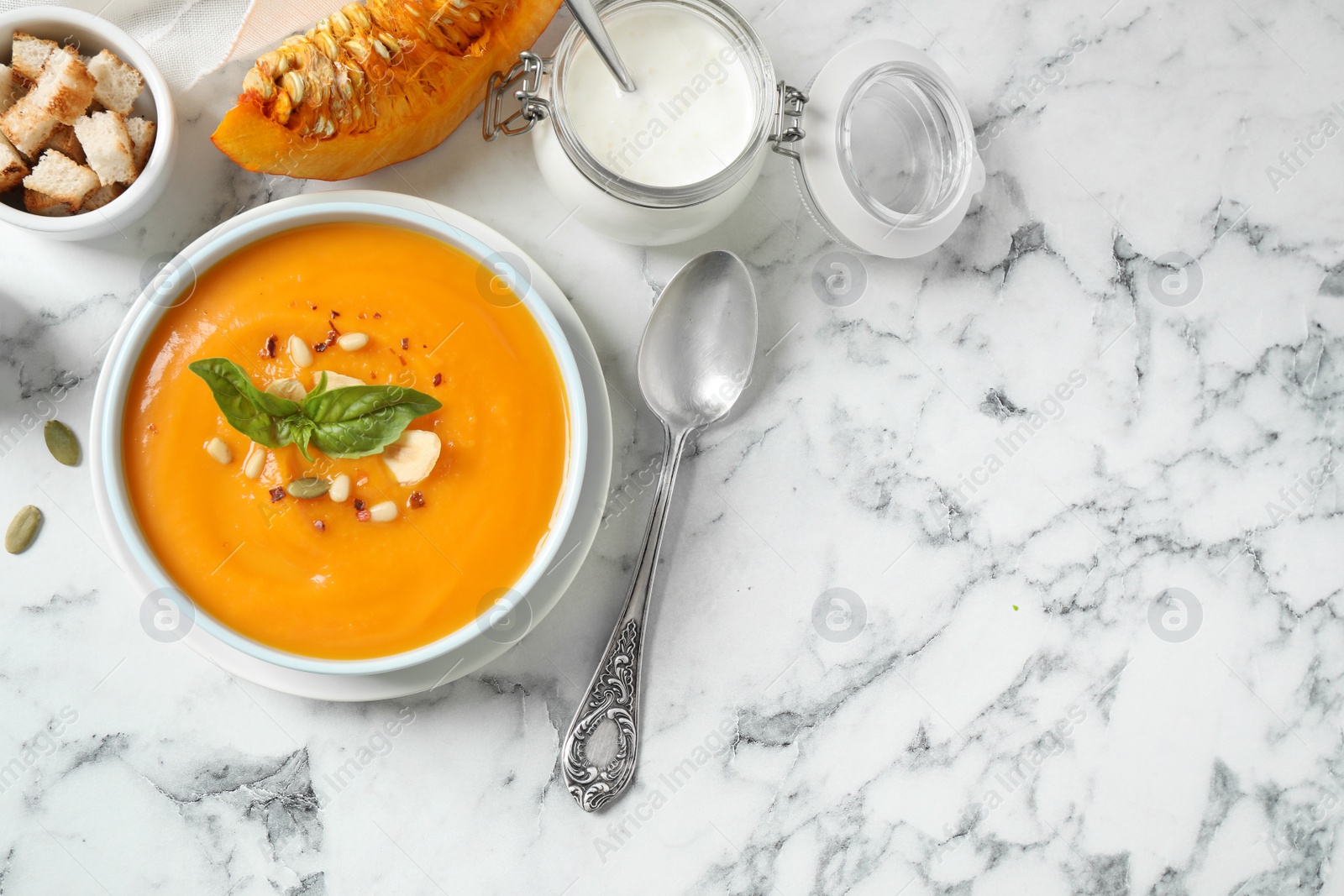 Photo of Delicious pumpkin soup in bowl on marble table, flat lay. Space for text