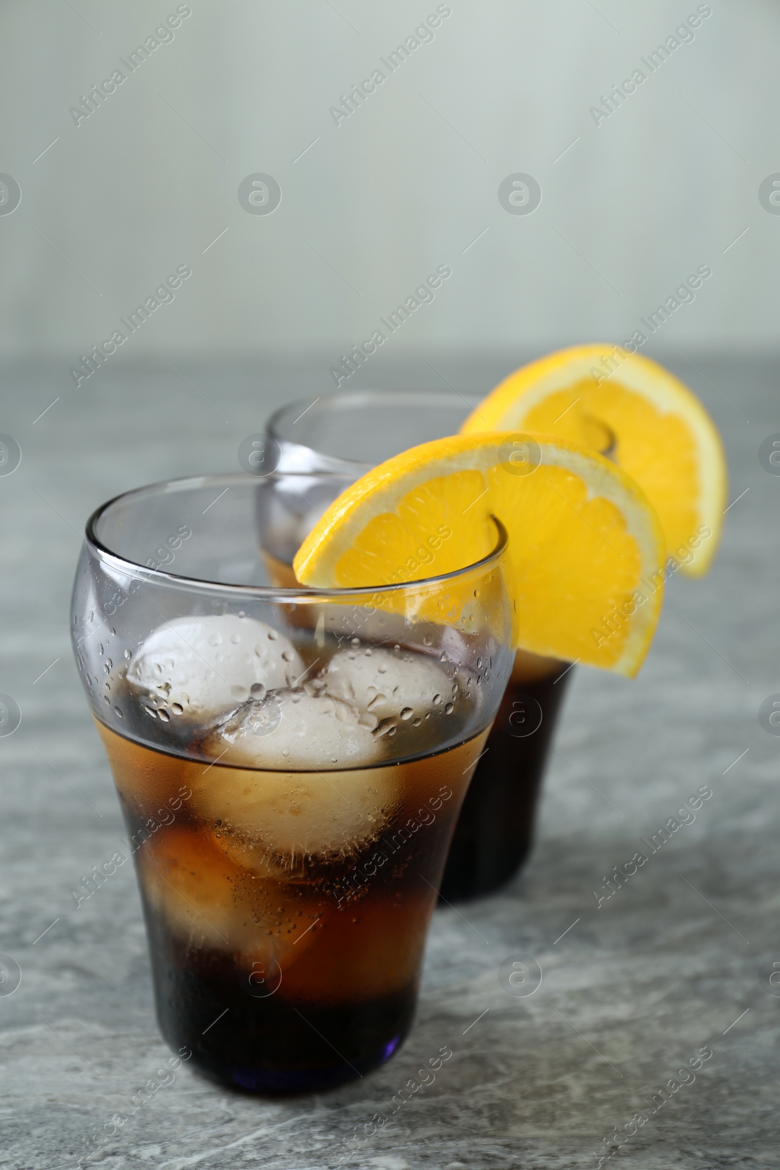 Photo of Delicious cocktails with orange and ice balls on grey table
