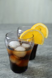 Photo of Delicious cocktails with orange and ice balls on grey table