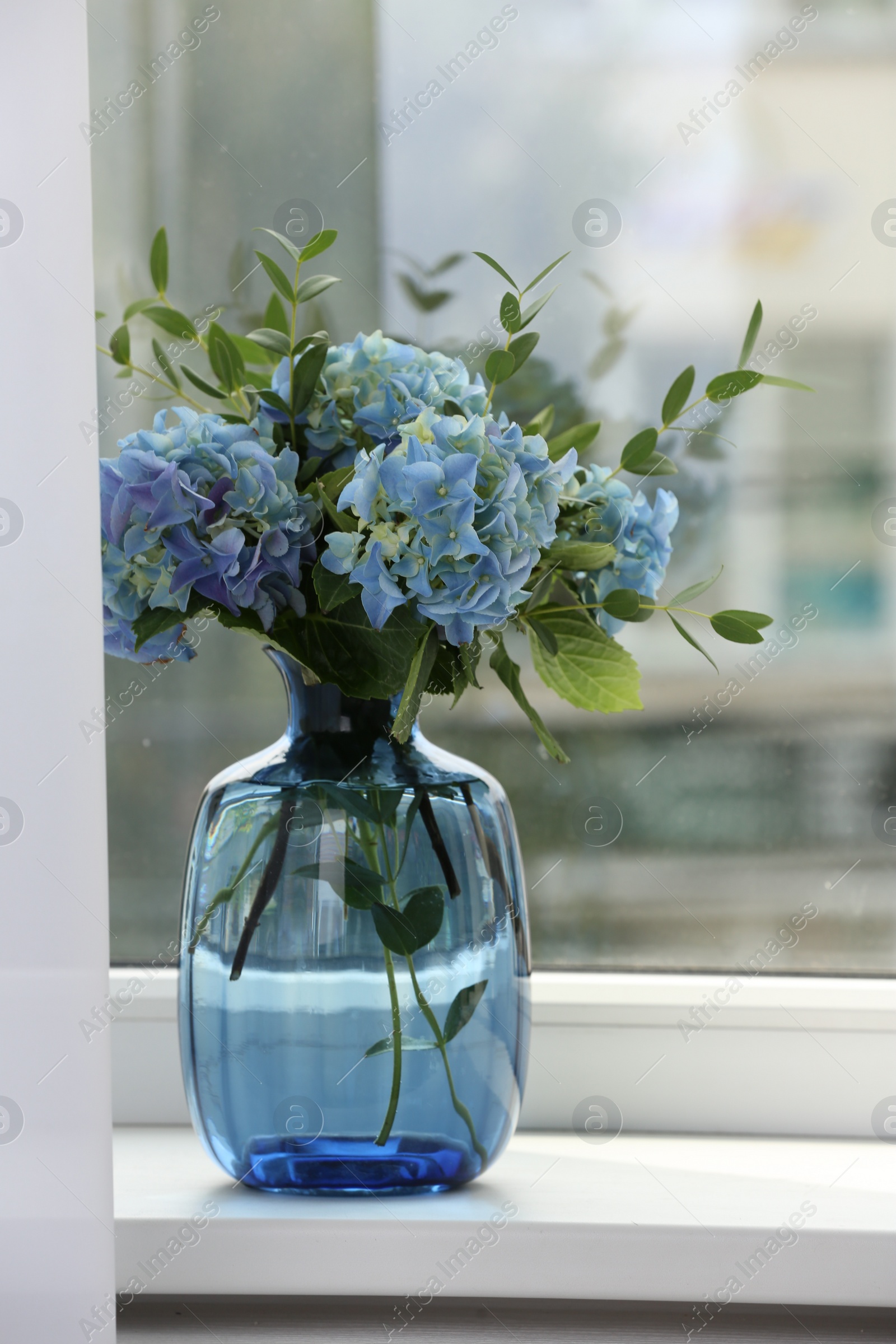 Photo of Beautiful blue hortensia flowers in vase on window sill indoors