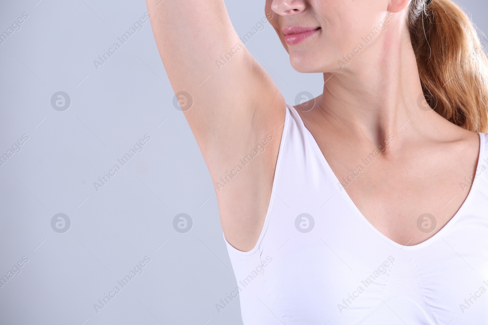 Photo of Young woman showing armpit on grey background, space for text. Using deodorant