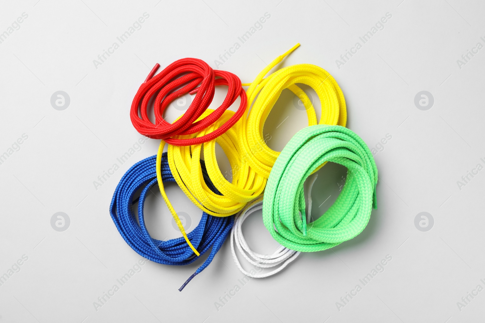 Photo of Colorful shoelaces on light background, flat lay