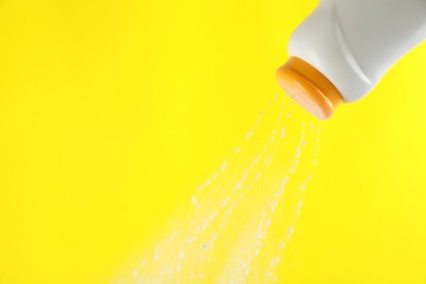 Photo of Scattering of dusting powder on yellow background, space for text