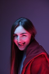 Photo of Portrait of happy woman on purple background in neon lights