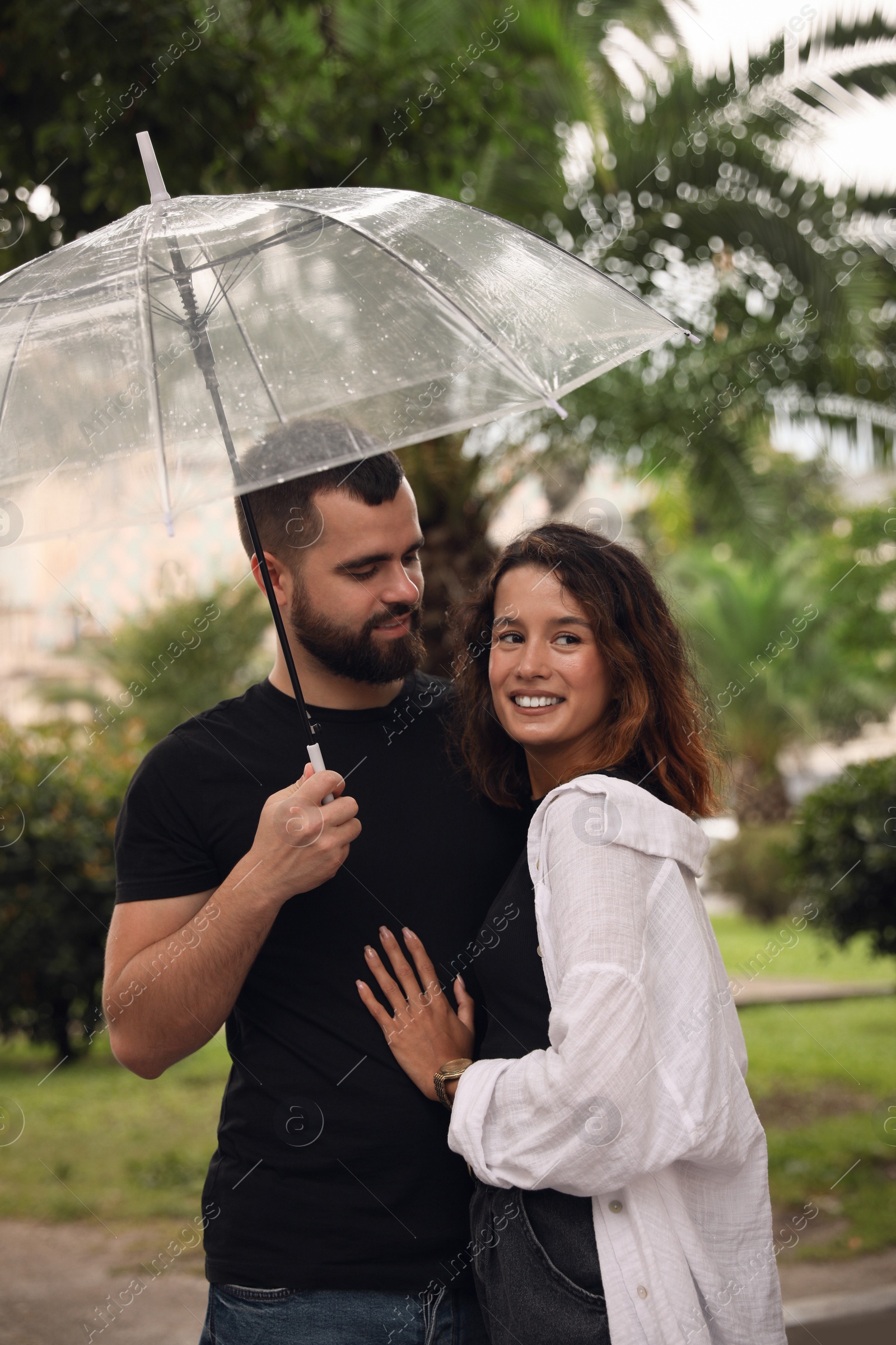 Photo of Young couple with umbrella enjoying time together under rain on city street