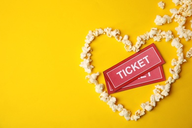 Cinema tickets and heart made of popcorn on color background, top view. Space for text