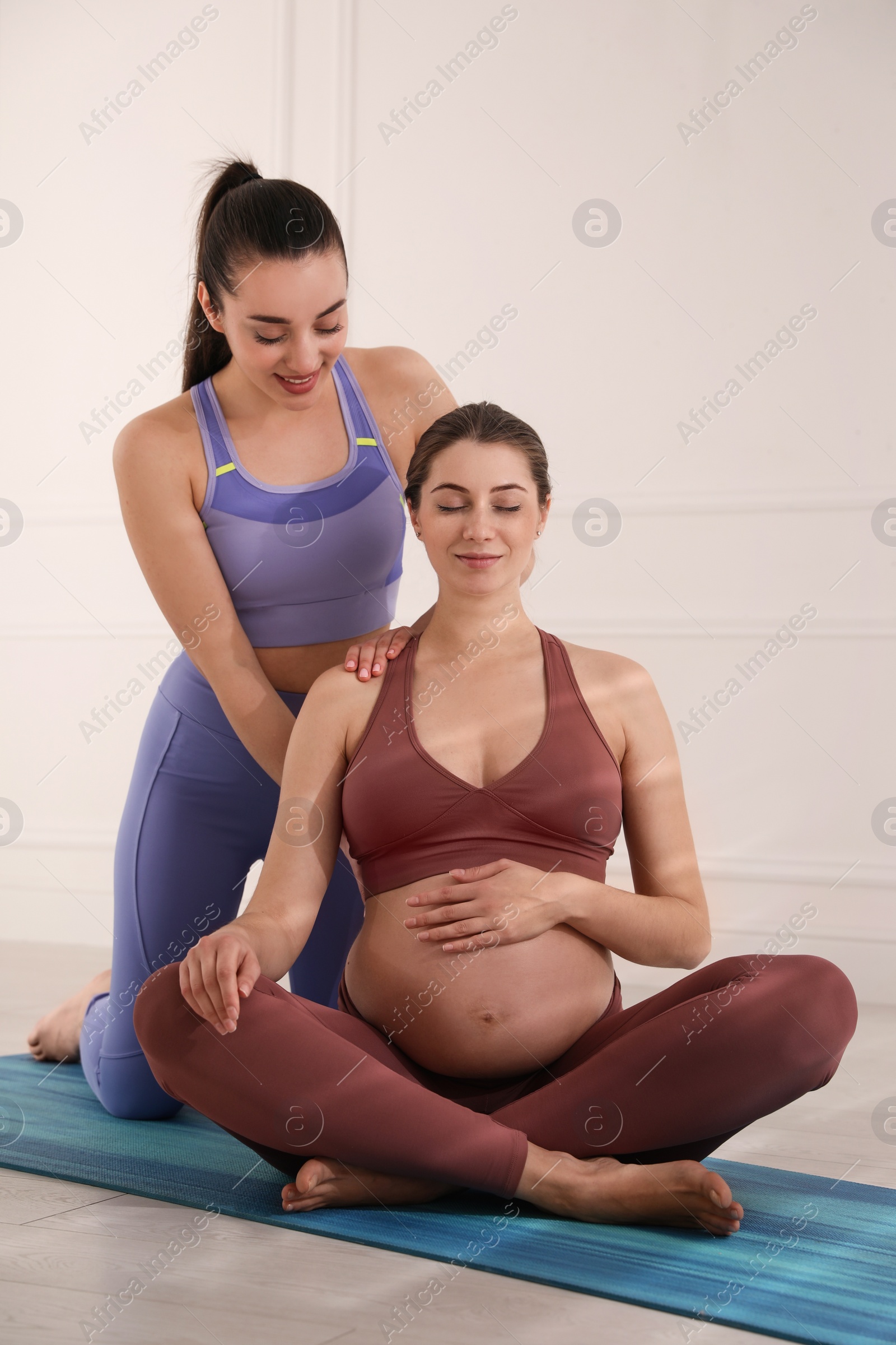 Photo of Trainer working with pregnant woman in gym. Preparation for child birth