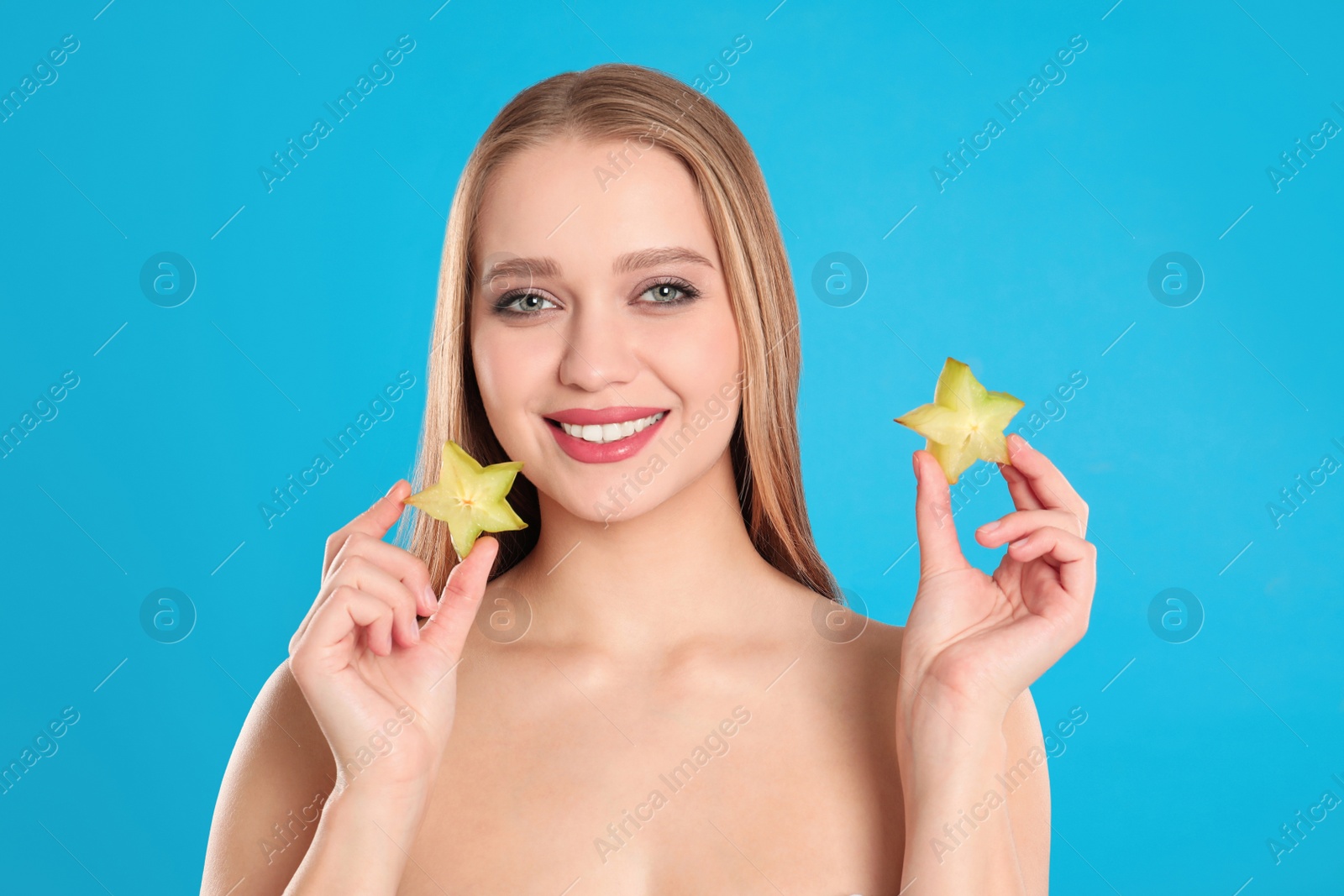 Photo of Young woman with cut carambola on blue background. Vitamin rich food