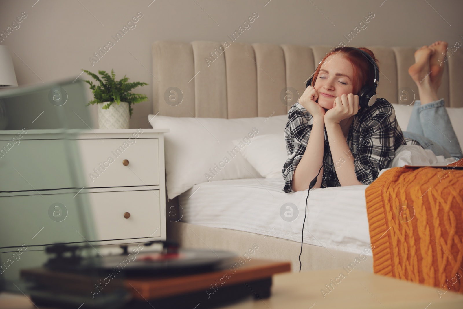 Photo of Young woman listening to music with turntable in bedroom