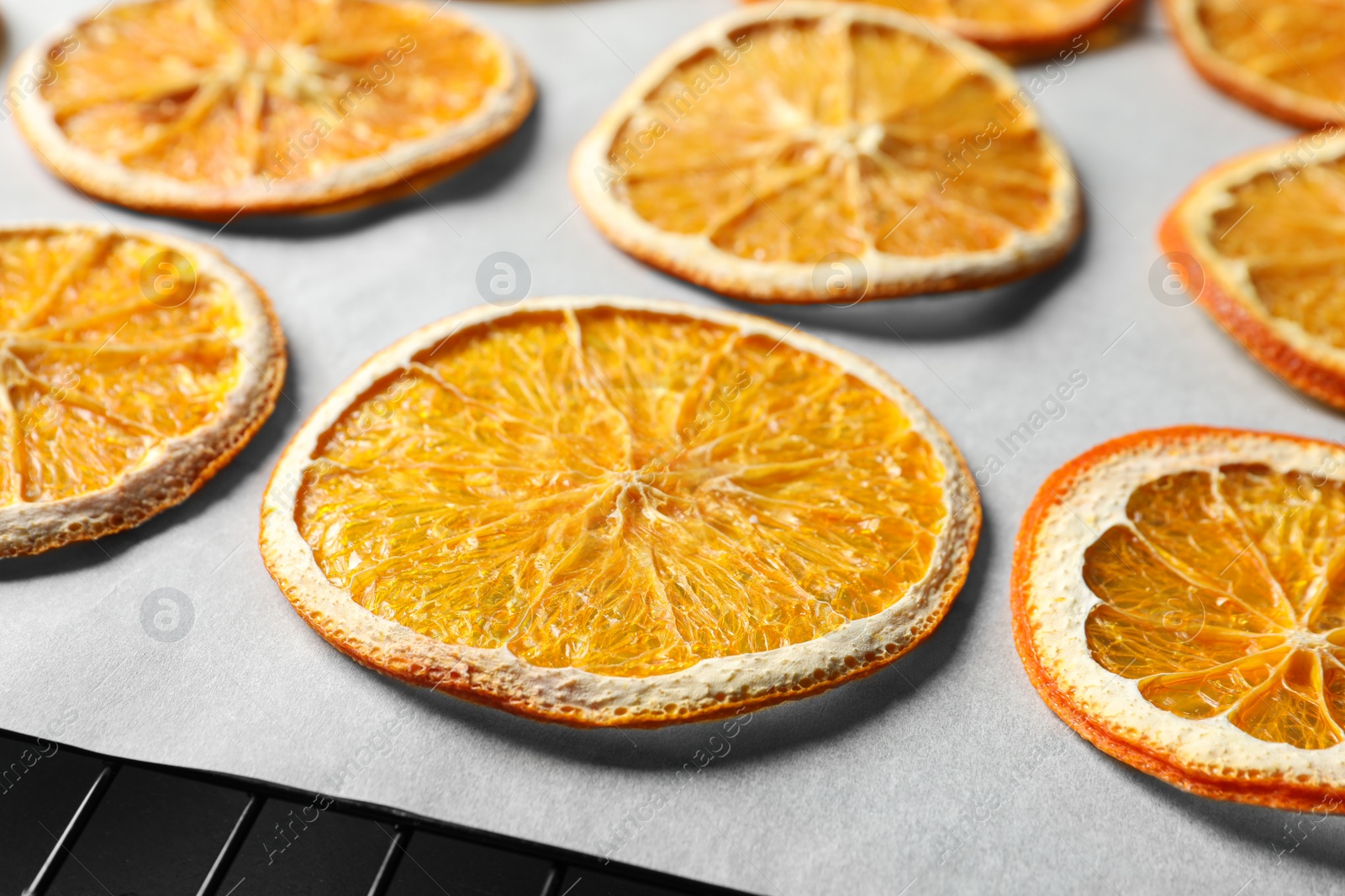 Photo of Dry orange slices on parchment paper, closeup