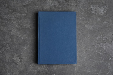 Photo of Hardcover book on grey stone table, top view. Space for text
