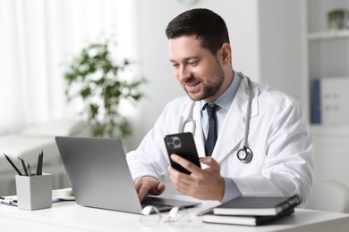 Photo of Doctor with gadgets having online consultation at table in clinic