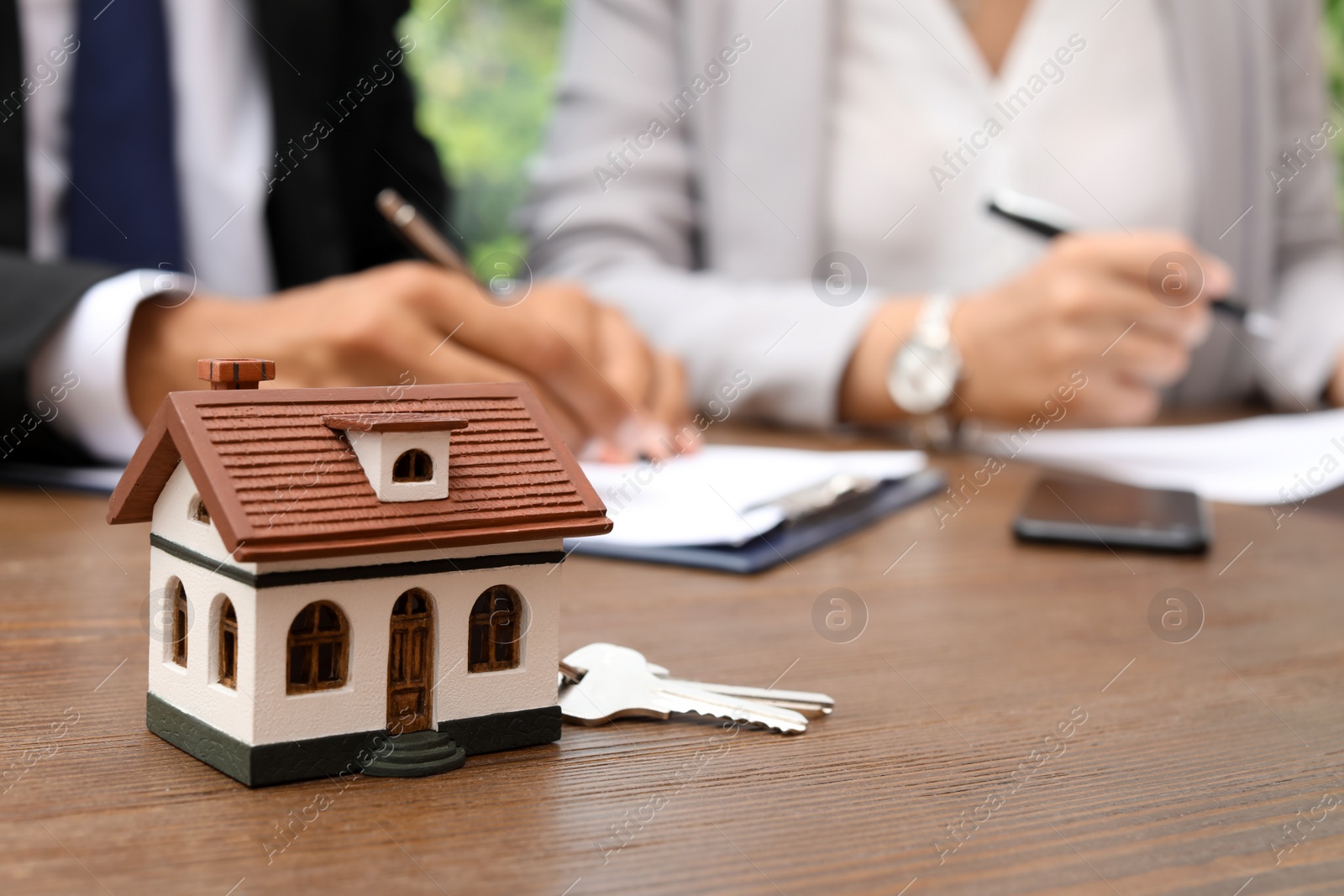 Photo of Keys and house model on table in real estate agent's office