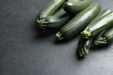 Photo of Green ripe zucchinis on black slate table. Space for text