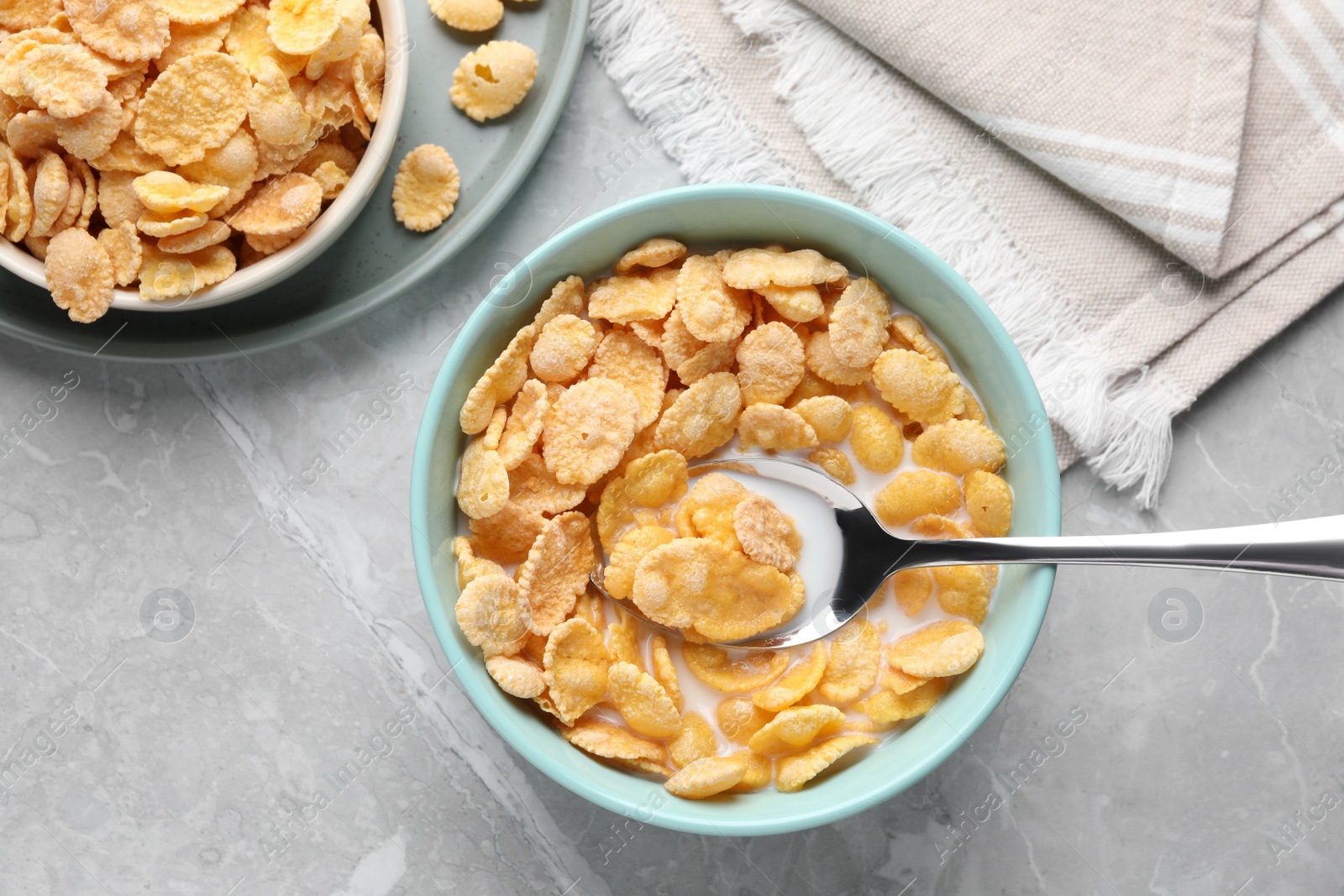 Photo of Tasty cornflakes with milk served on light grey table, flat lay