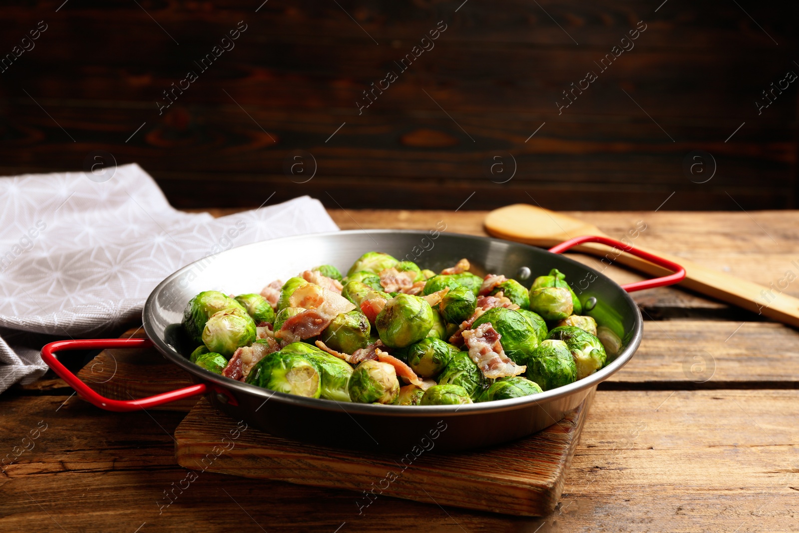 Photo of Delicious Brussels sprouts with bacon on wooden table