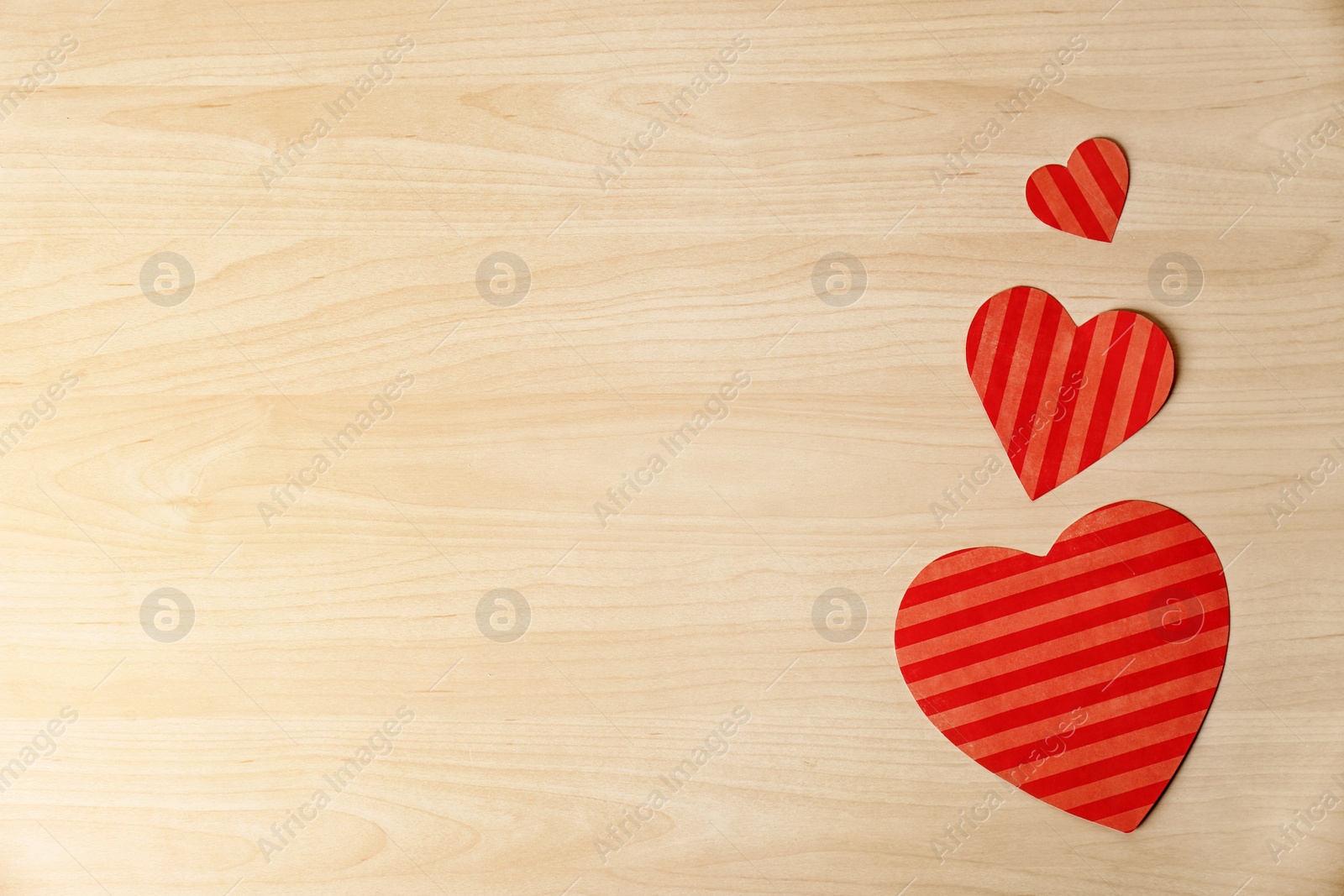 Photo of Color paper hearts and space for text on wooden background, top view