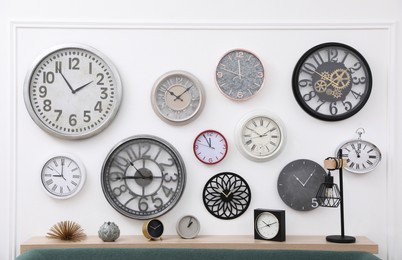 Photo of Collection of different clocks on white wall in room