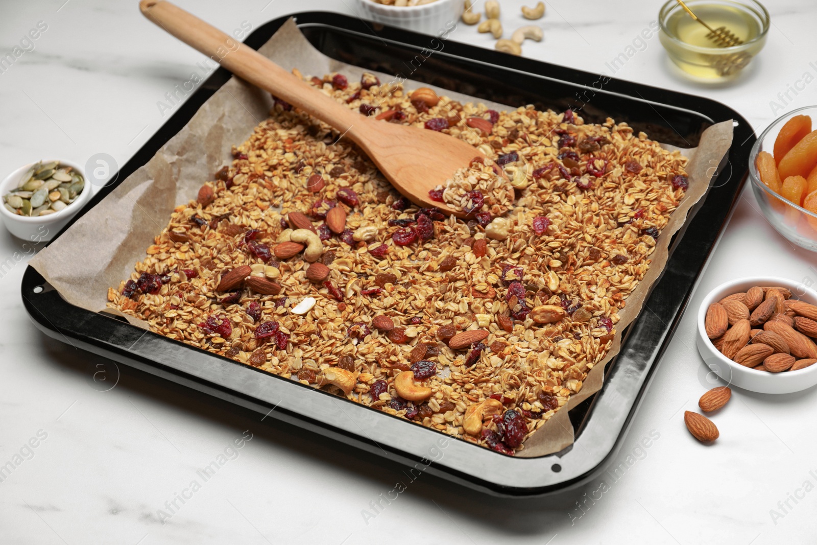Photo of Tray with tasty granola, nuts and dry fruits on white marble table