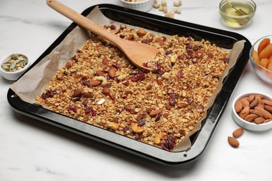 Tray with tasty granola, nuts and dry fruits on white marble table