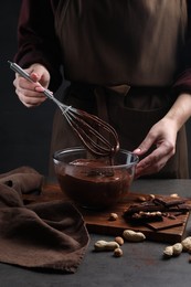 Photo of Woman with whisk mixing delicious chocolate cream at table, closeup