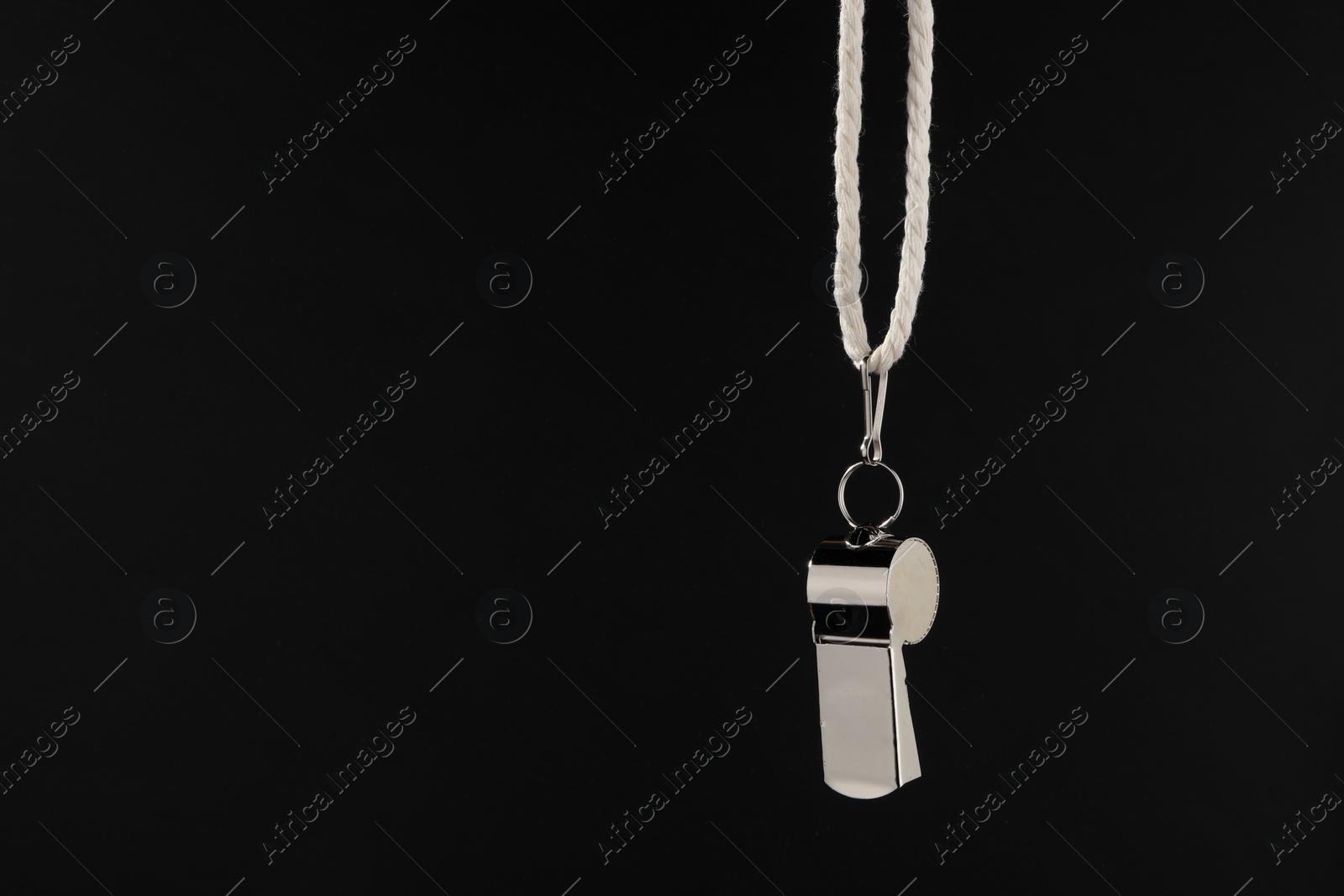 Photo of Referee equipment. Metal whistle on black background, closeup and space for text