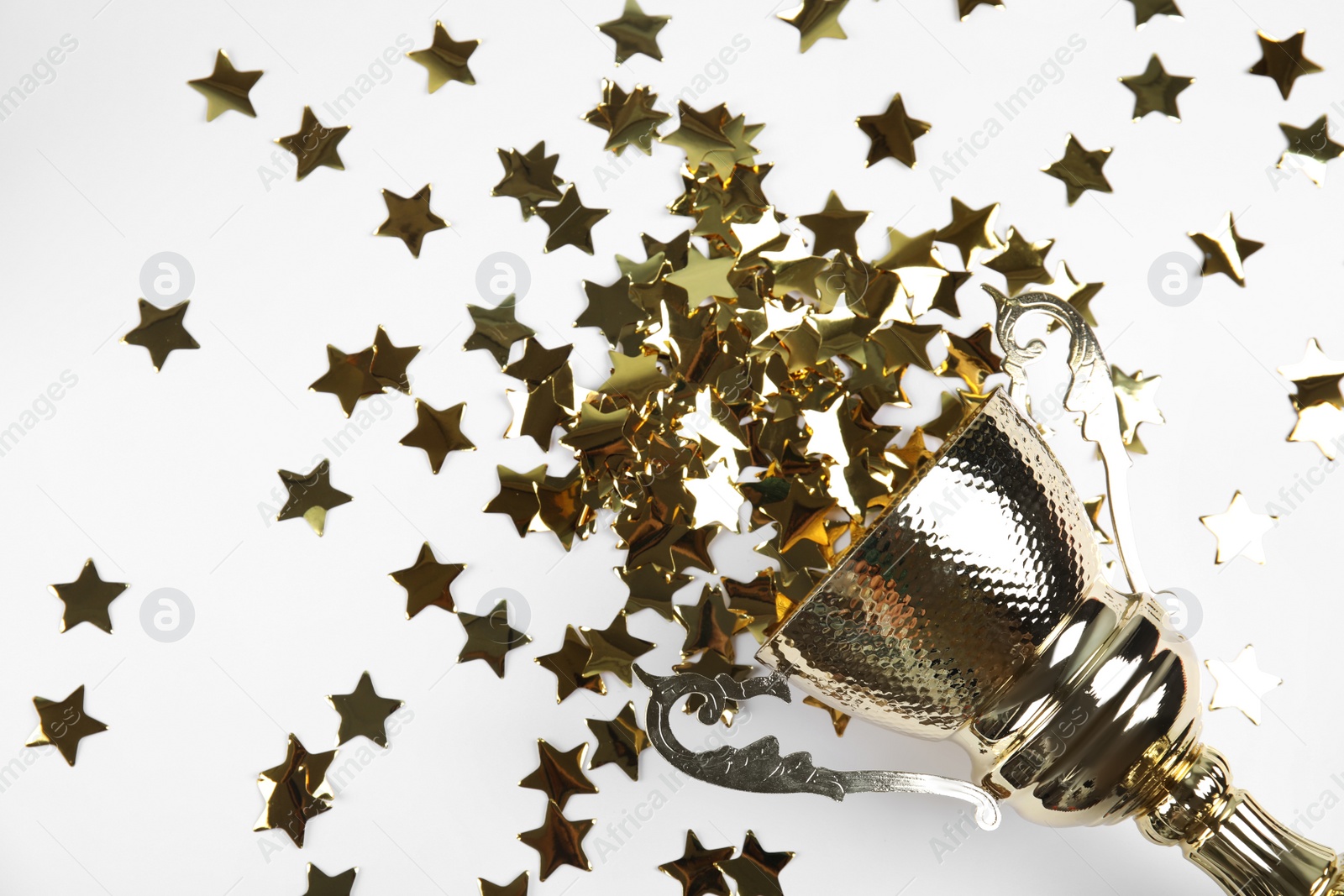 Photo of Gold trophy cup and confetti on white background, top view