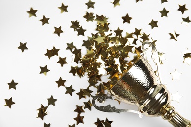 Gold trophy cup and confetti on white background, top view