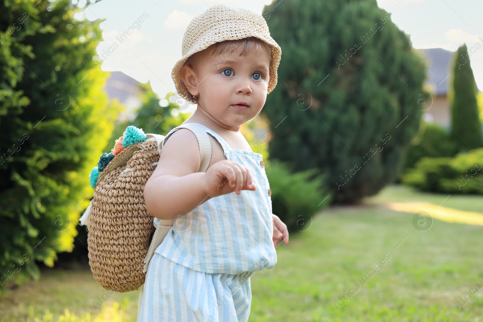 Photo of Cute little girl in stylish clothes with knitted backpack outdoors on sunny day. Space for text