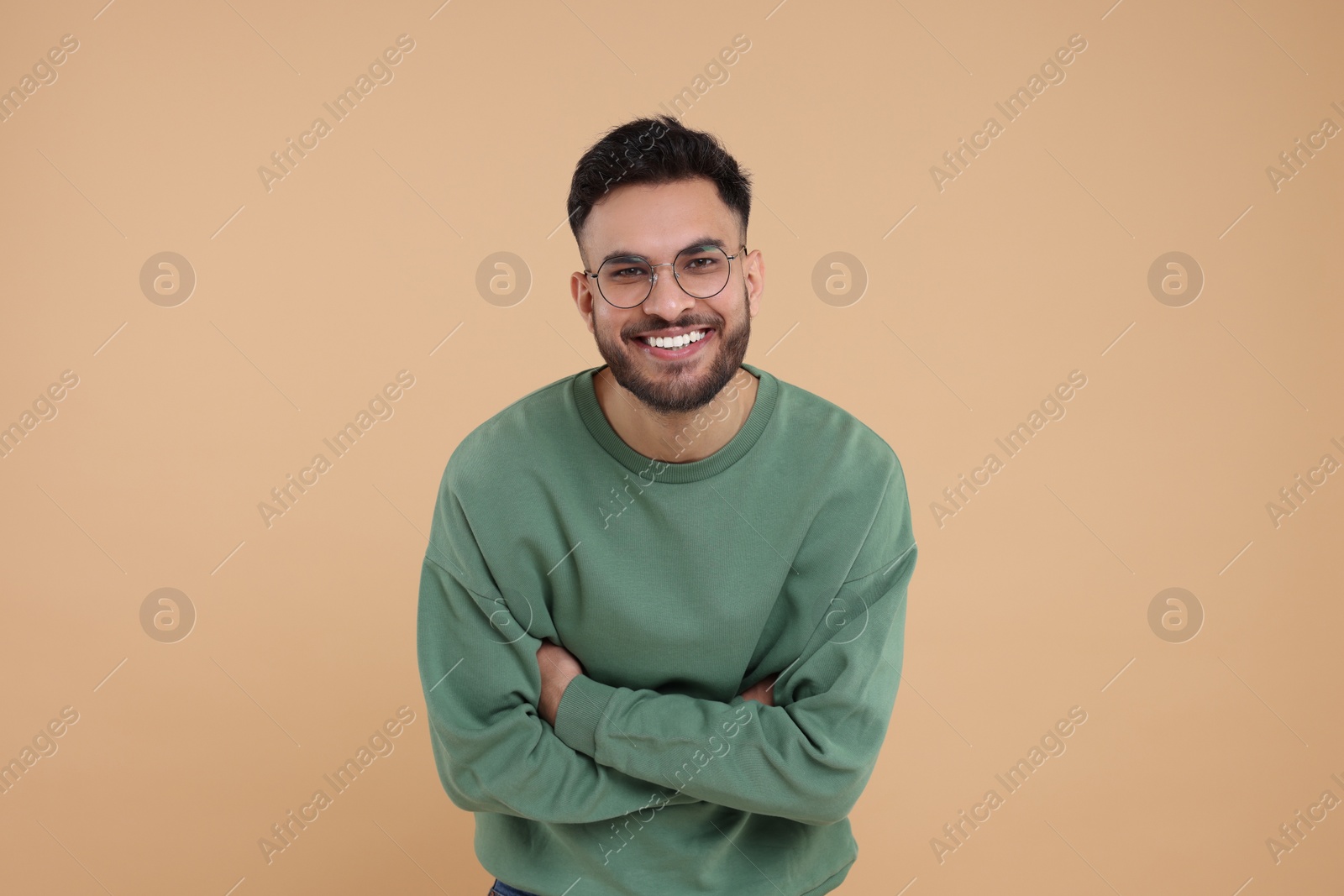 Photo of Handsome young man laughing on beige background