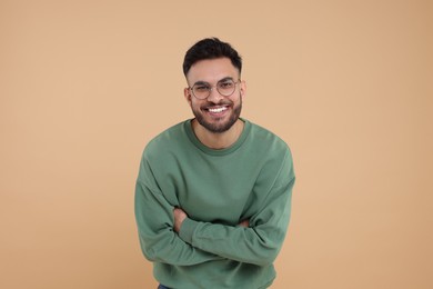 Handsome young man laughing on beige background