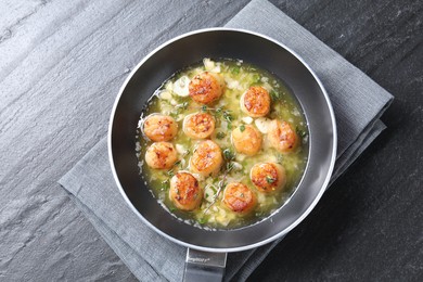 Delicious scallops with sauce in frying pan on dark gray textured table, top view