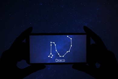 Woman using stargazing app on her phone at night, closeup. Identified stick figure pattern of Dragon (Draco) constellation on device screen
