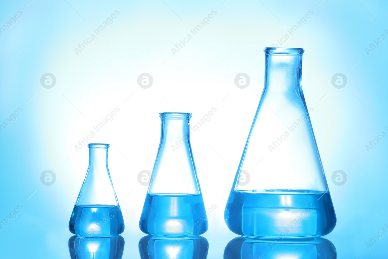 Photo of Laboratory glassware with liquid on color background. Solution chemistry