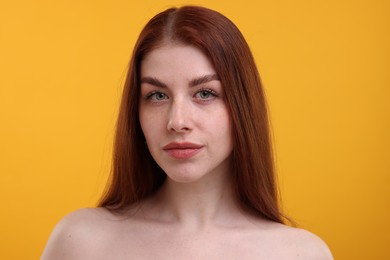 Portrait of beautiful woman with freckles on yellow background