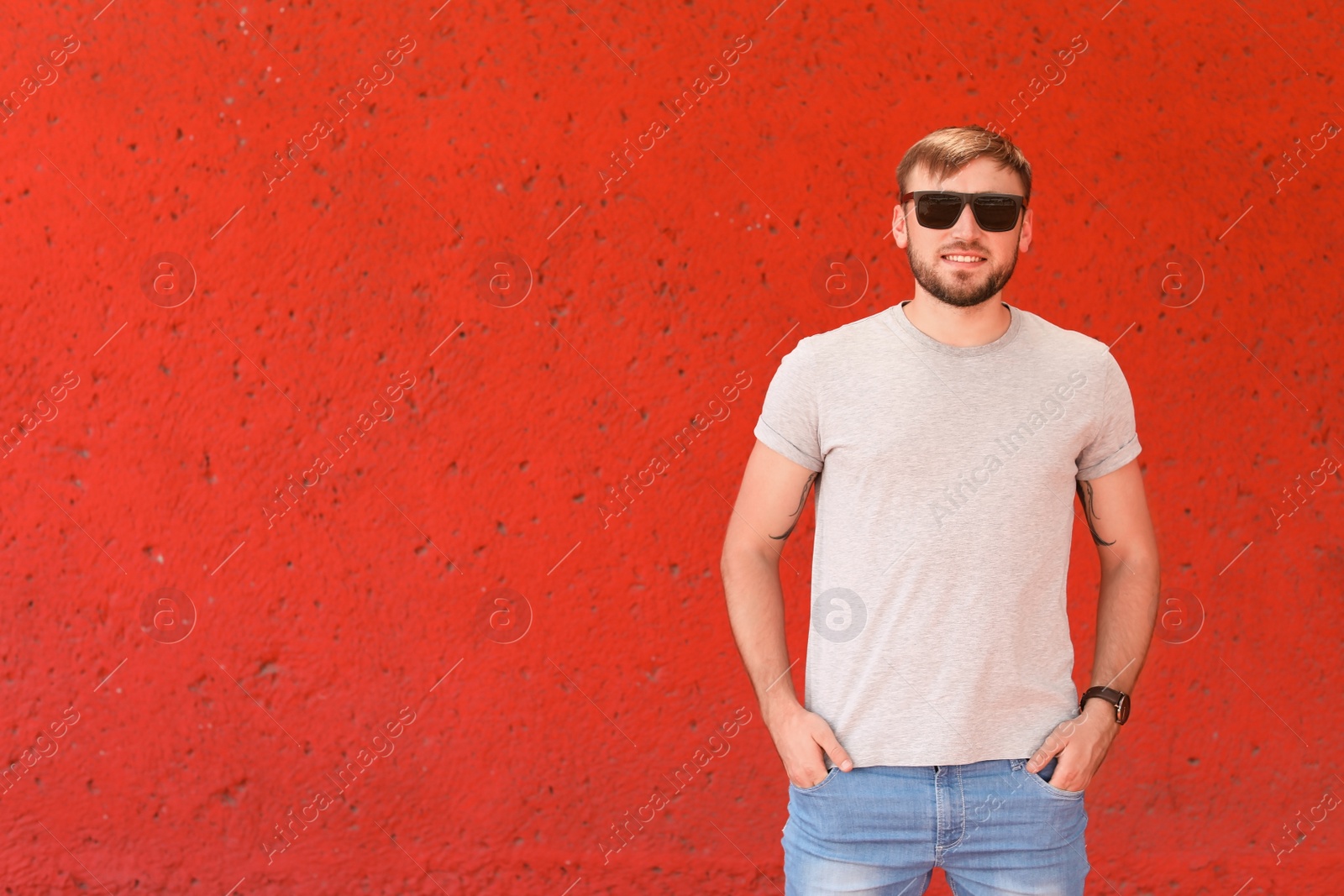 Photo of Young man wearing gray t-shirt near color wall on street