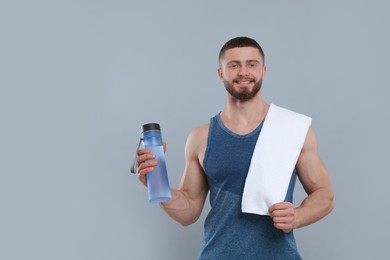 Photo of Handsome sportsman with bottle of water and white towel on grey background, space for text
