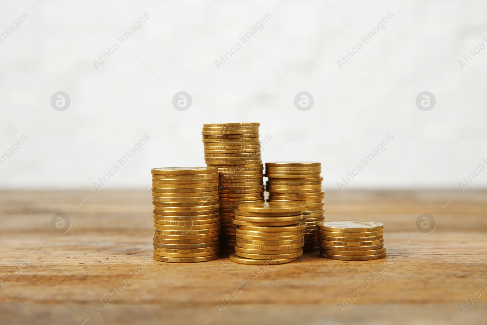 Photo of Many stacks of coins on table against light background