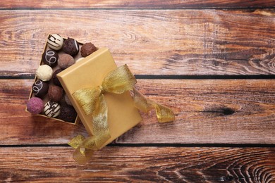 Photo of Open box with delicious chocolate candies on wooden table, top view. Space for text