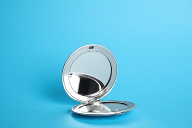 Photo of Stylish cosmetic pocket mirror on light blue background