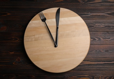 Photo of Empty board and cutlery on wooden table, top view. Diet regime