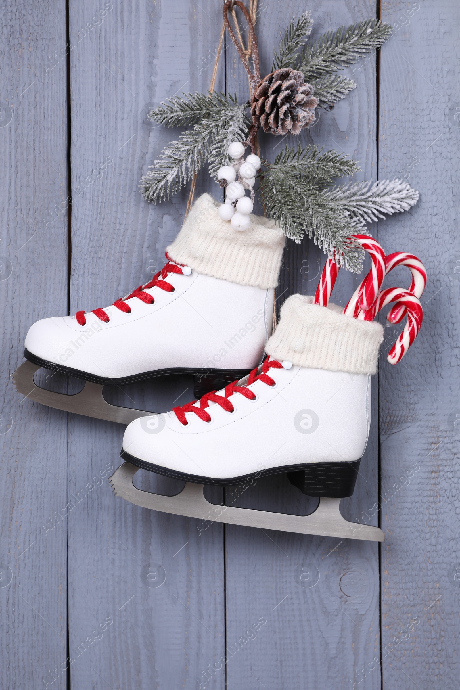 Photo of Pair of ice skates with Christmas decor hanging on grey wooden wall