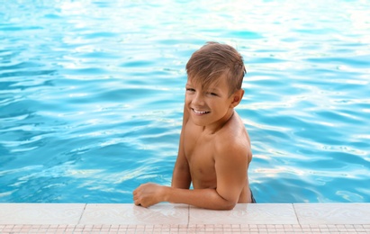 Happy cute boy in swimming pool on sunny day