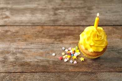 Photo of Delicious birthday cupcake with candle on wooden background